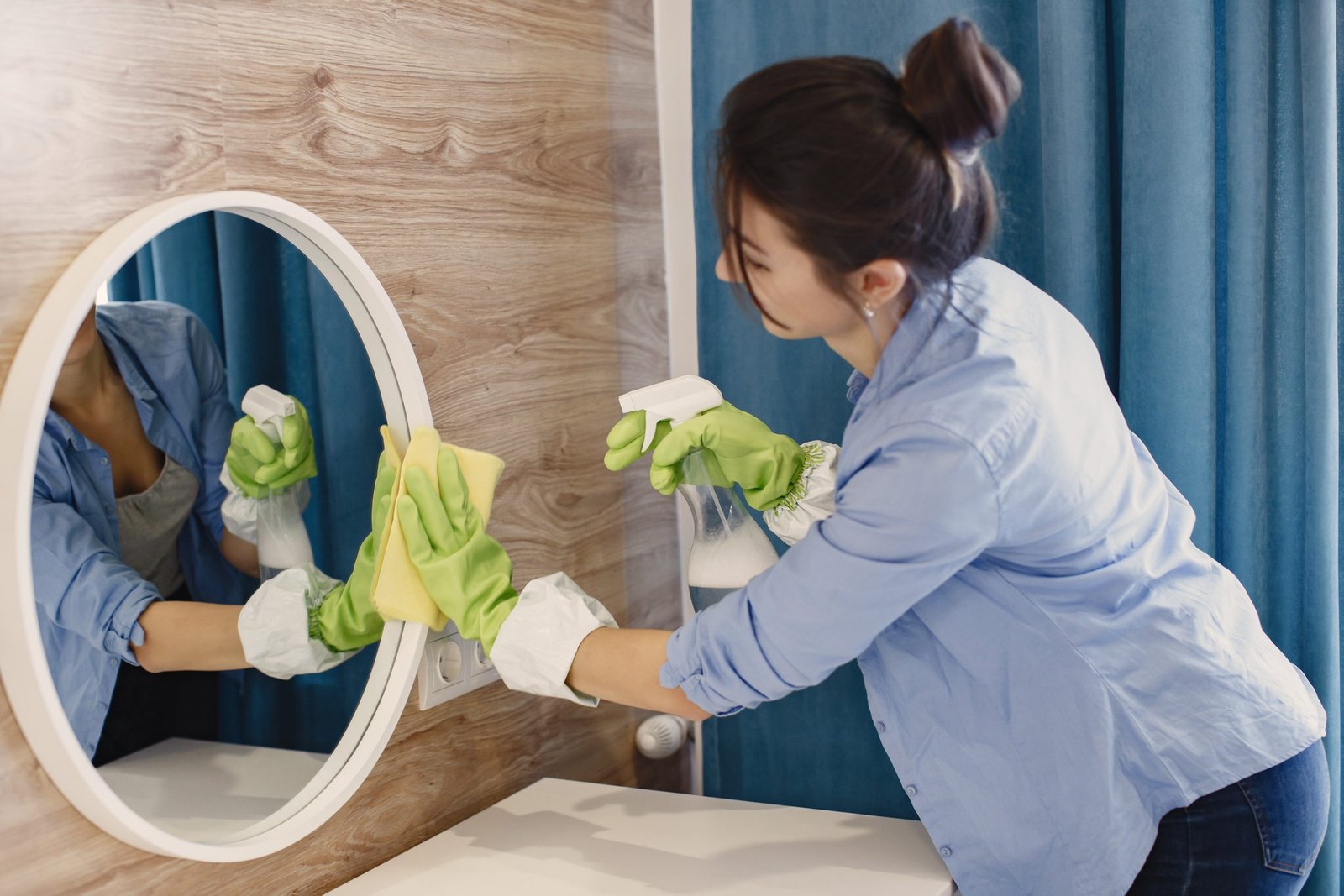 Cleaner wiping a mirror during a residential house cleaning